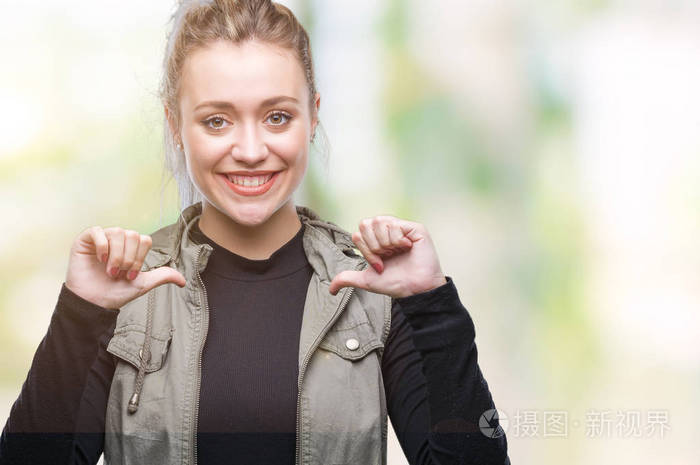 年轻的金发女人在孤立的背景下脸上露出自信的笑容用手指自豪和快乐地