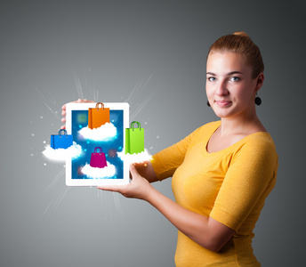女人在云上举行现代平板电脑与彩色购物袋