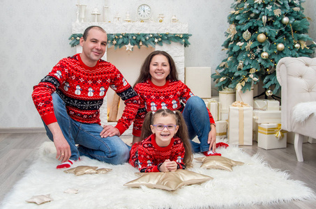 幸福的家庭在红色毛衣在一个房间装饰圣诞前夜