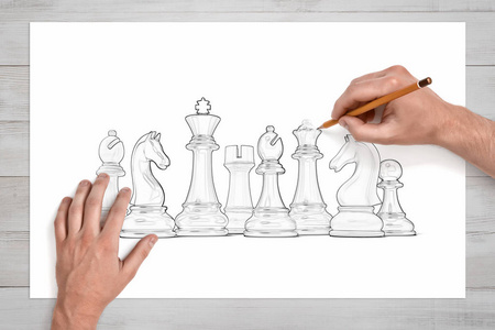 男性手用铅笔在纸上画一整套白棋片