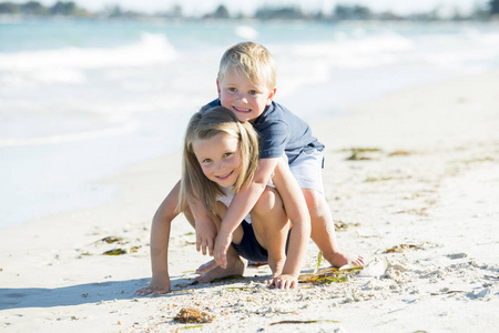 小可爱和甜美的兄弟姐妹一起玩沙滩与弟弟拥抱他美丽的金发妹妹享受假期