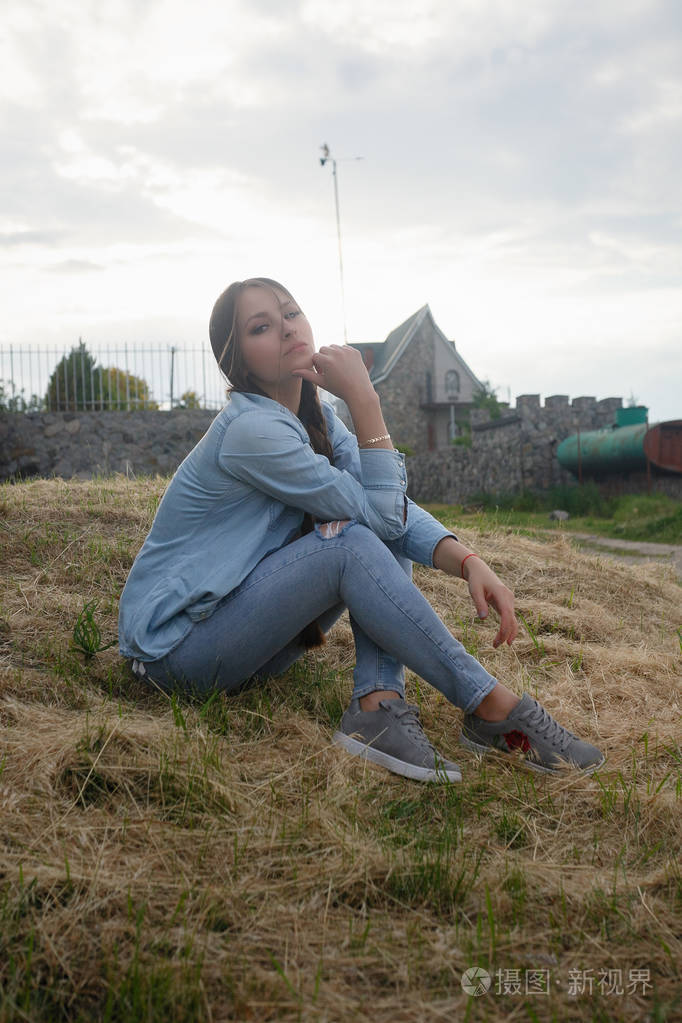 一个美丽的浪漫年轻女子在乡下日落的肖像.牛仔服装迷人的女孩