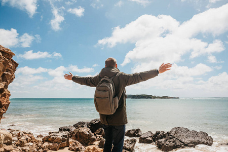 葡萄牙大西洋沿岸的一个背包游客或旅行者举起双手