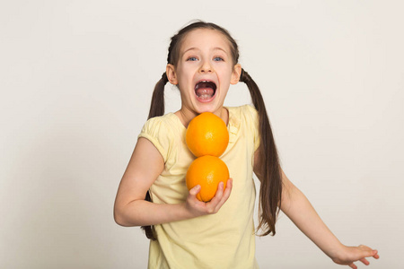 快乐的小女孩与桔子的乐趣在白色背景