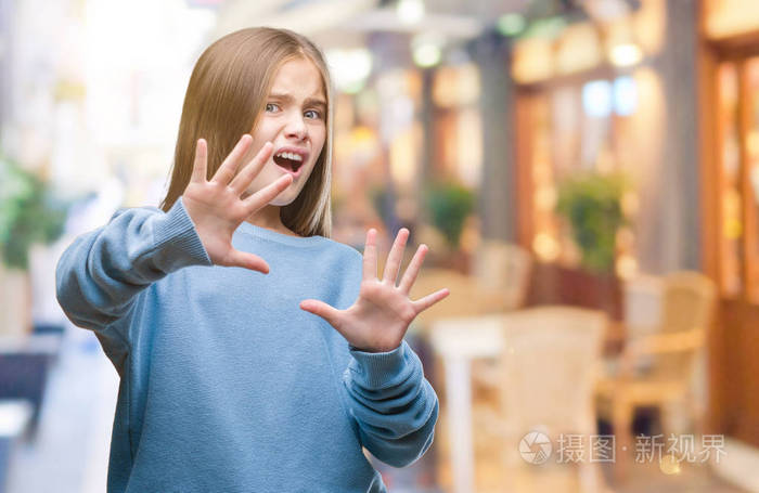 年轻美丽的女孩穿着冬天的毛衣在孤立的背景害怕和恐惧的表情停止手势