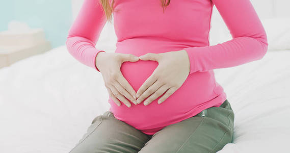 关闭孕妇在腹部形成心脏形状