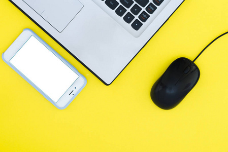 智能手机和笔记本电脑的黄色背景下的鼠标。顶部视图。平躺