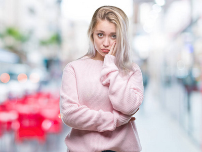 年轻的金发女人穿着冬季毛衣在孤立的背景下思考看累了, 厌倦了与交叉臂抑郁症问题