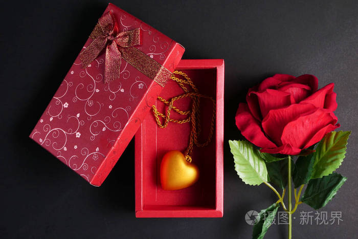 红玫瑰与金心项链在红色礼品盒黑色背景情人节概念