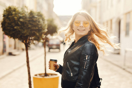 漂亮女孩站在街上喝着咖啡