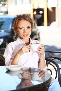 美丽的年轻女子坐在咖啡馆