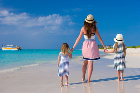 年轻的母亲和两个她时尚的孩子在异国海滩上阳光灿烂的日子