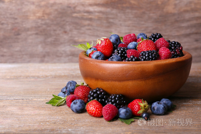 成熟甜的不同的莓果在碗里，老木桌上