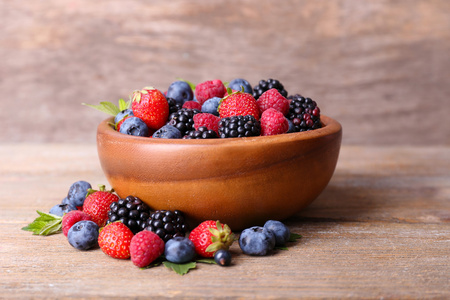成熟甜的不同的莓果在碗里，老木桌上