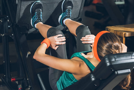 运动妇女训练腿在训练用具在健身房