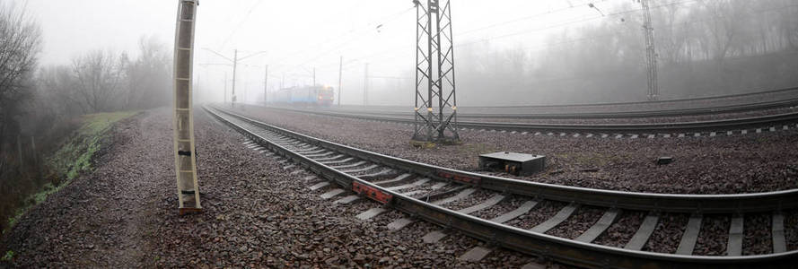 乌克兰郊区的火车在一个薄雾的早晨沿着铁路飞驰而过。鱼眼照片与失真增加