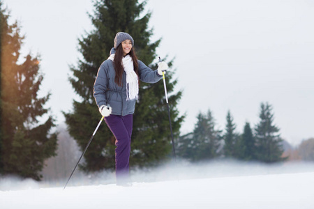 冬天女孩在温暖的运动服滑雪在公园或森林在周末