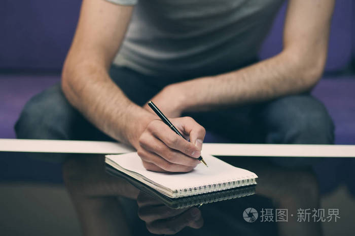 坐在沙发上的人在笔记本上写字