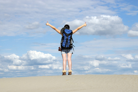 女孩徒步旅行者在沙漠中竖起大拇指