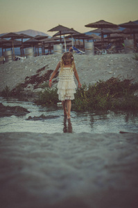 女孩站在海滩上, 蓝色的天空背后