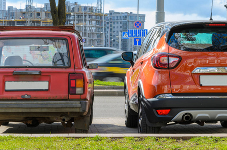 两辆汽车的后视图并排站在城市的不同时代技术发展的概念照片