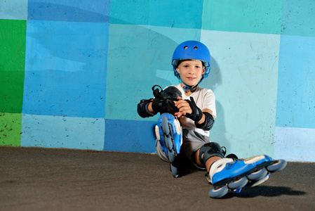 可爱的小运动男孩坐在蓝色涂鸦墙上的滚筒上
