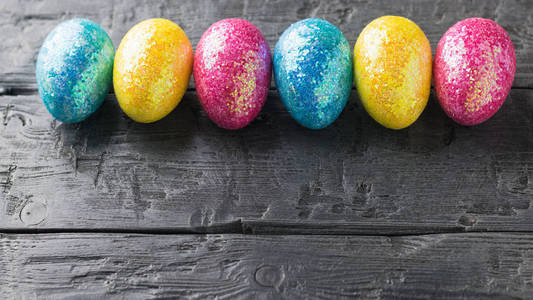 五彩的复活节彩蛋放在一张木桌上的水平线上。复活节餐桌的装饰