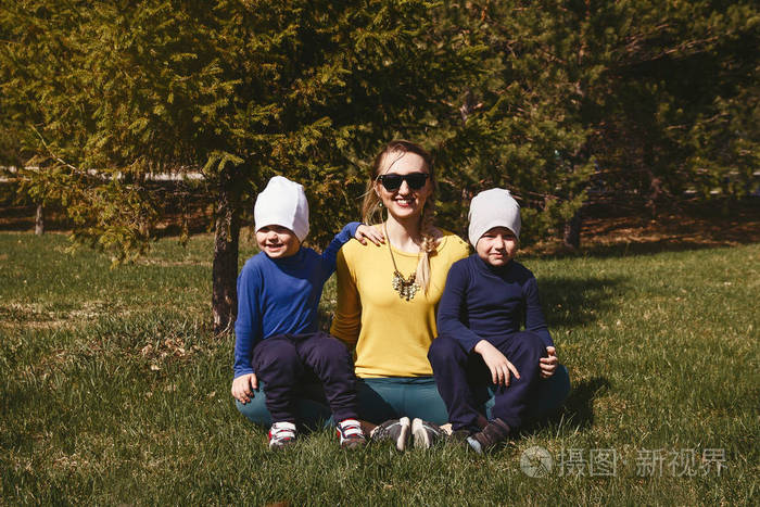 妈妈带着两个儿子坐在公园的草地上