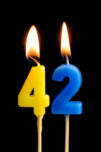 燃烧蜡烛的形式为42四十二 数字, 日期 的蛋糕孤立的黑色背景。庆祝生日周年纪念日重要日期节日餐桌设置的概念
