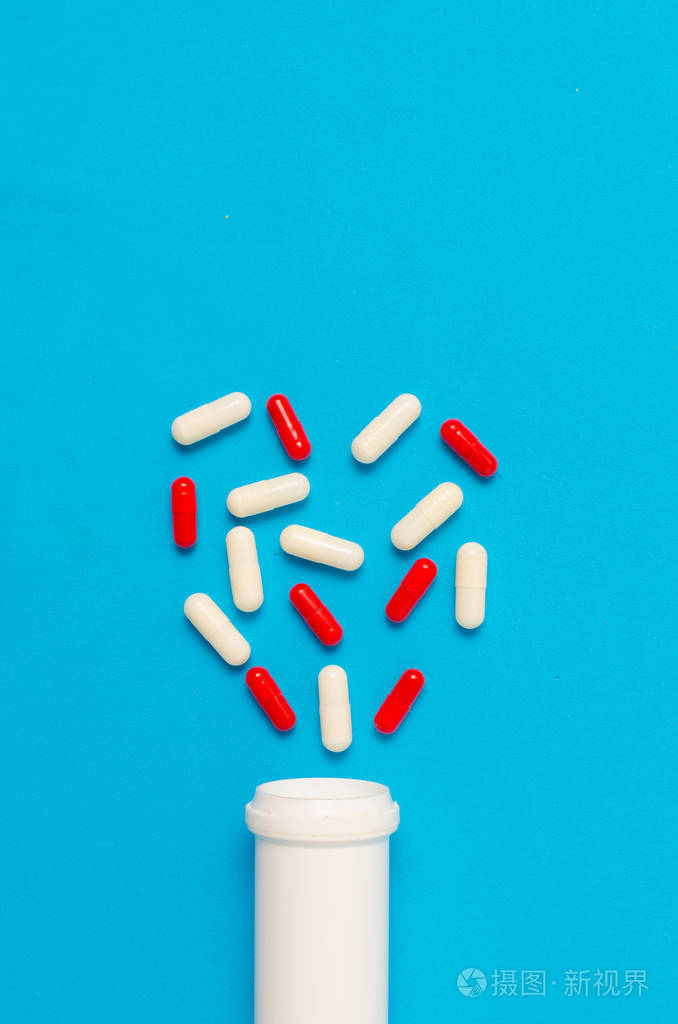 各种片剂和药片蓝色背景下的药物和抗生素心形瓶