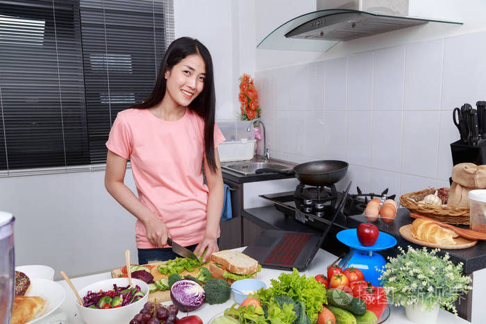 厨房里的女人做饭和看笔记本电脑