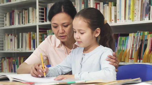 可爱的小女孩做家庭作业与她的母亲