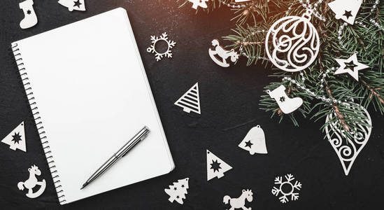 笔记本为圣诞节笔记在黑石头背景。用木制玩具装饰的冷杉树。顶部视图。文本空间