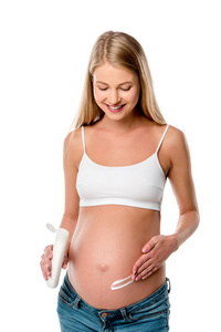 有吸引力的怀孕妇女应用化妆水在她的腹部, 以避免在白色查出的妊娠纹