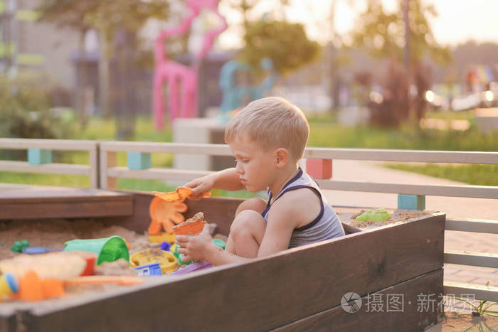 现代城市的儿童生活小男孩在院子里的沙箱里玩耍