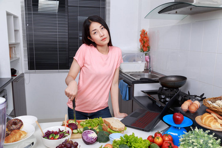 厨房里的女人做饭和看笔记本电脑