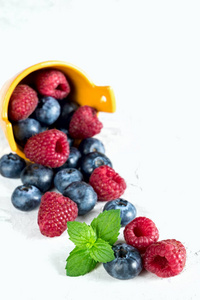 蓝莓和覆盆子的浆果, 从篮子里倒入, 白色背景
