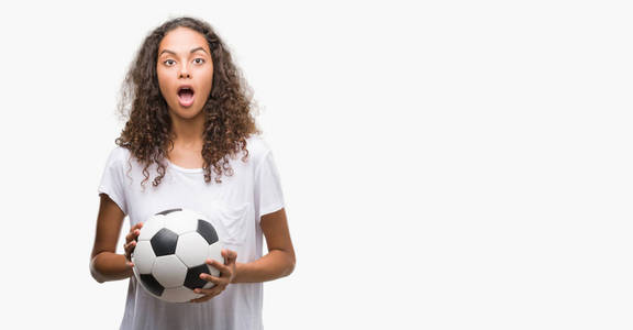 年轻的西班牙裔女子拿着足球球吓坏了, 吓得一惊脸, 害怕和激动的表情