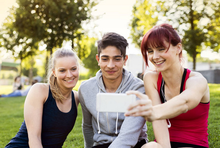 一群年轻的跑步者带着智能手机在公园里