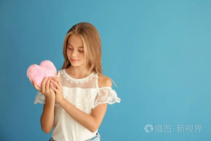 可爱的小女孩与毛绒心脏在颜色背景