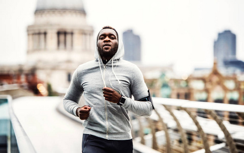 年轻运动的黑人赛跑者奔跑在桥梁外面在城市