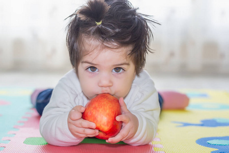 可爱可爱的小女婴的肖像抱着吃一个大红苹果