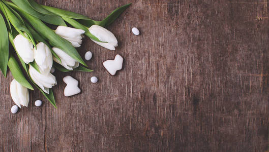 在木桌上用白色郁金香和釉状曲奇做成的花朵组成的兔子