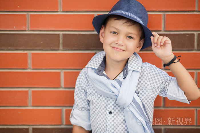 时尚男孩在砖墙上摆姿势的帽子