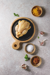 生有机生料全黄玉米迷你鸡在木制切板上加盐姜黄香料粉红辣椒罗勒蒜灰背景。烹饪理念。平躺, 空间