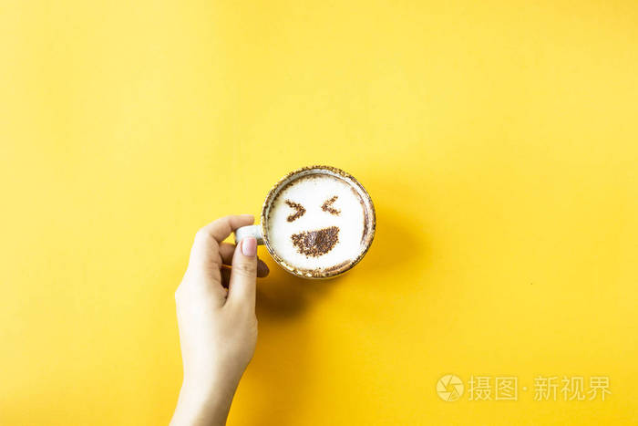 一只雌性的手捧着一杯咖啡上面画着emoji表情的笑声情感在社会网络