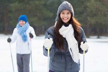 愉快的年轻妇女与牙齿微笑在森林滑雪与她的男朋友在休闲