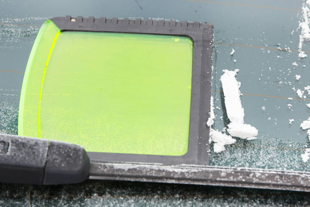 冬季汽车挡风玻璃上的绿色冰刮板
