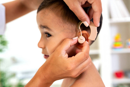 医生对儿童耳部的助听器医疗装置的安置