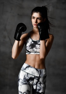 年轻美丽的女人框教练拳击在混凝土阁楼墙背景黑色手套